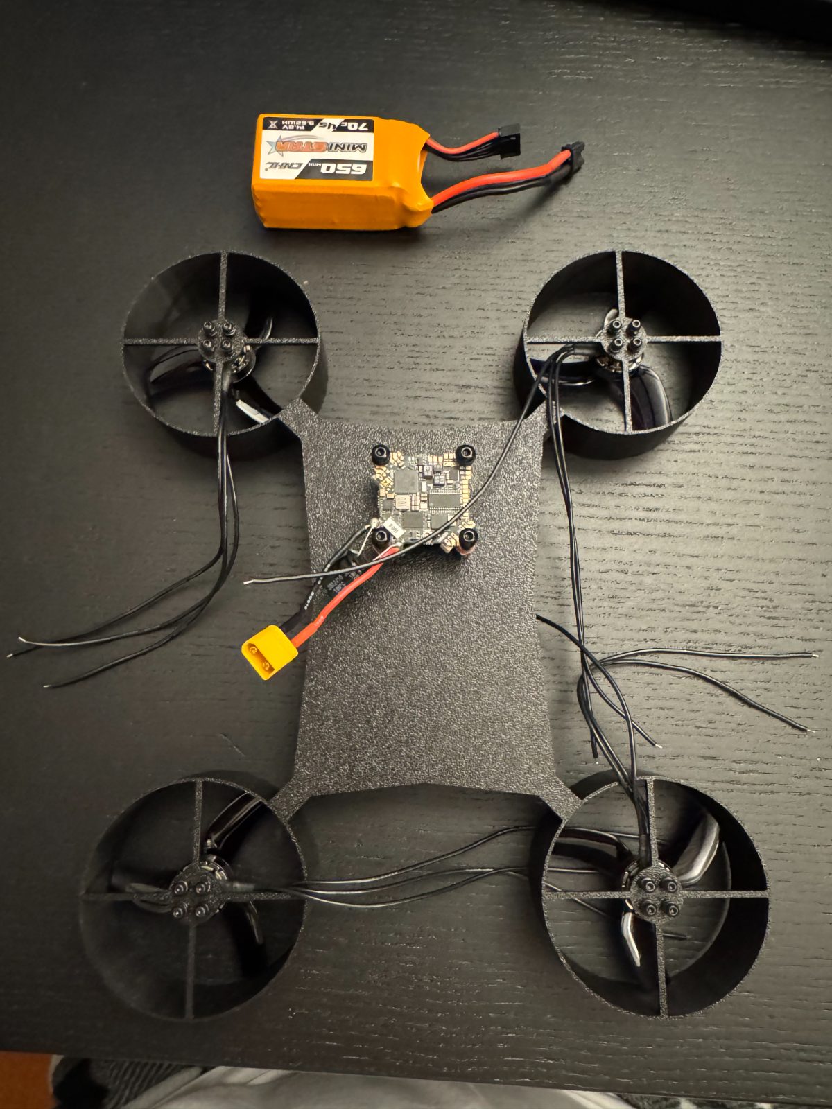 Cinewhoop components laid out: printed ducted frame, flight controller, motors and battery